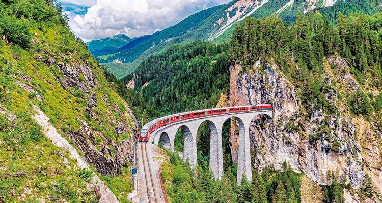 Malerische Eisenbahnbrücke über eine tiefe Schlucht, umgeben von Wäldern.