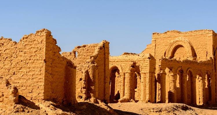 Ruines d'un ancien temple du désert avec des colonnes et des arches.