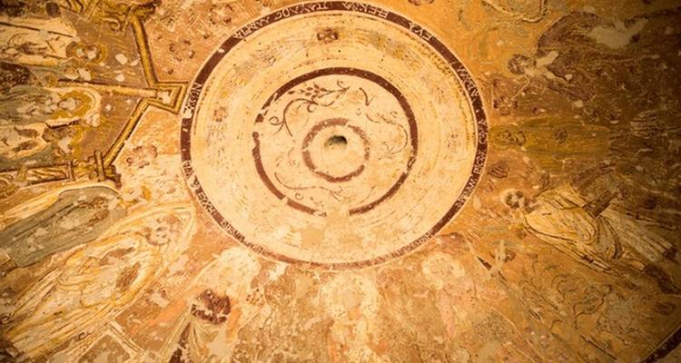 Plafond à coupole décorative avec sculptures et symboles religieux.