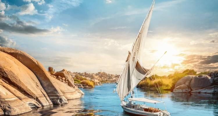 Voilier naviguant sur une rivière sereine aux rives rocheuses.