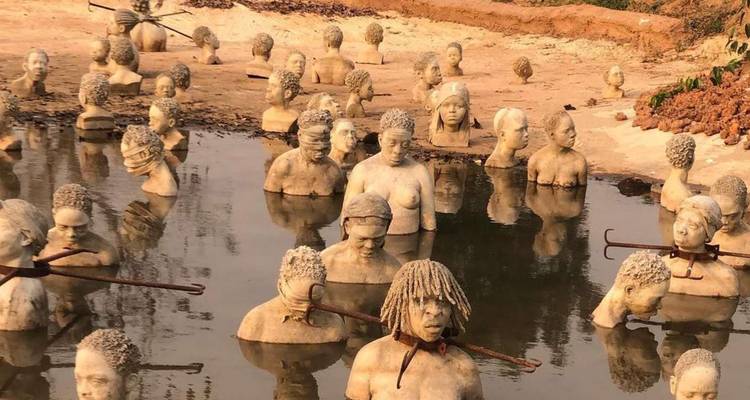 Esculturas de concreto de personas parcialmente sumergidas en agua.