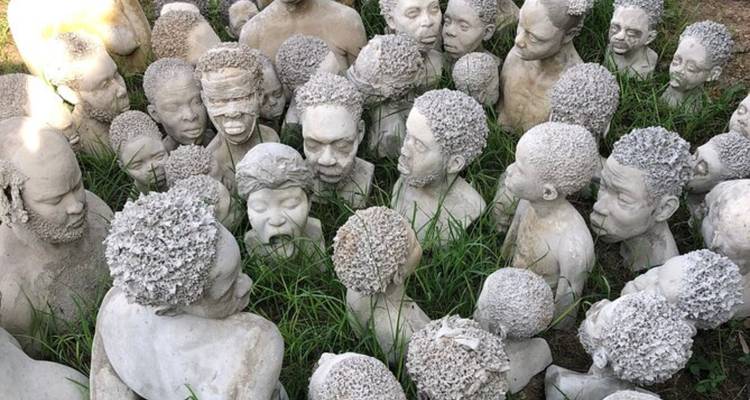 Esculturas de concreto de personas en disposición circular en el suelo.