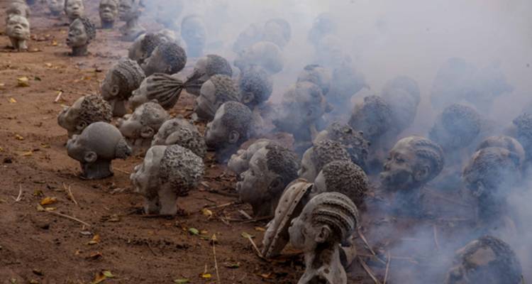 Esculturas de cabezas de concreto con humo o niebla a su alrededor.