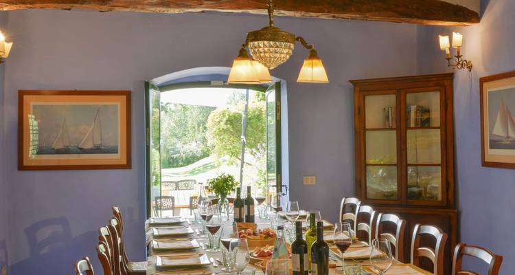 Salle à manger avec une longue table dressée pour un repas, donnant sur un jardin.