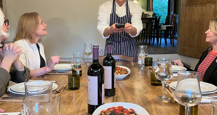 Chef parlant aux invités à une table de salle à manger avec du vin.