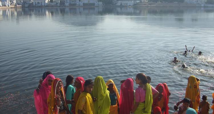 Gruppe von Frauen in farbenfrohen Kleidern am Wasser.