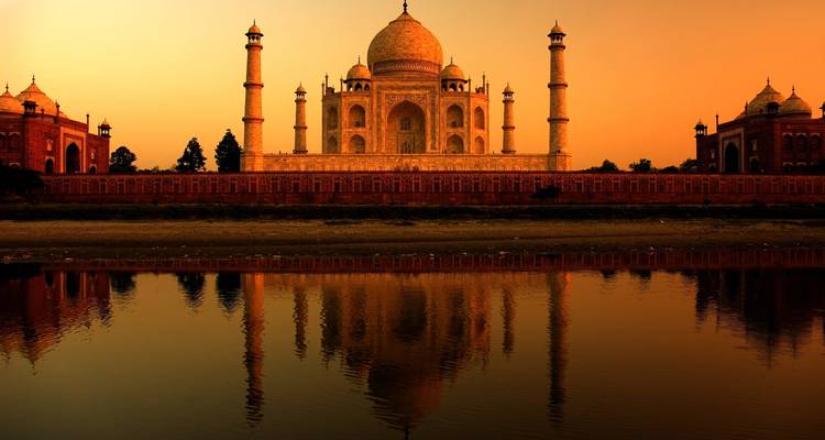 Das Taj Mahal spiegelt sich bei Sonnenuntergang im Fluss.