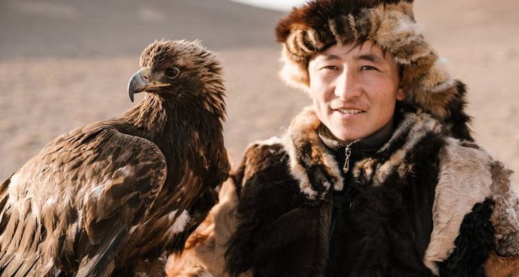Retrato de un hombre con atuendo tradicional de piel sosteniendo un águila.