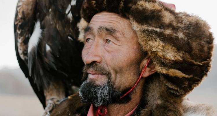 Retrato de primer plano de un hombre vistiendo atuendo tradicional mongol con un águila.