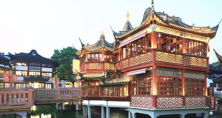 Traditioneel sierlijk Chinees gebouw bij het water bij schemering.