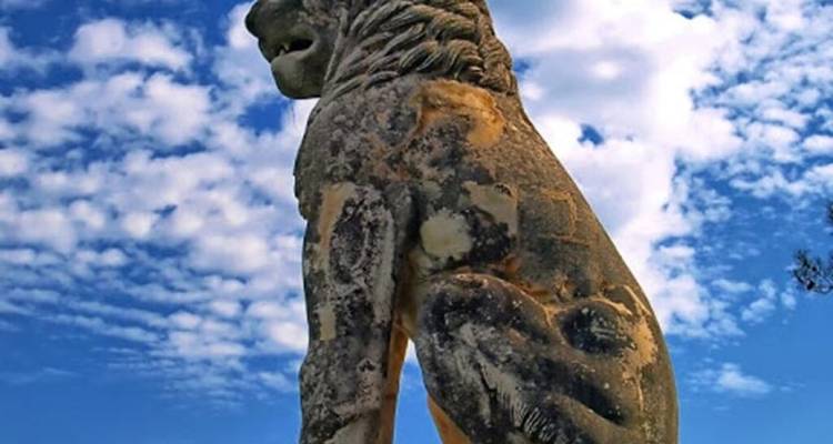 Gran estatua de león esculpida con un cielo nublado dinámico detrás.