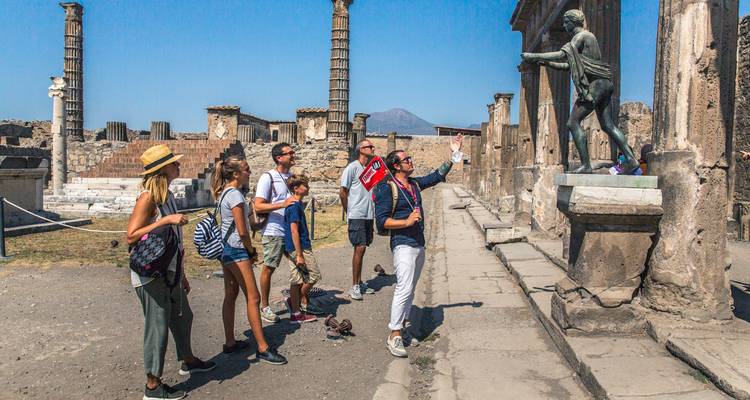 Un grupo de turistas admirando una estatua entre ruinas.