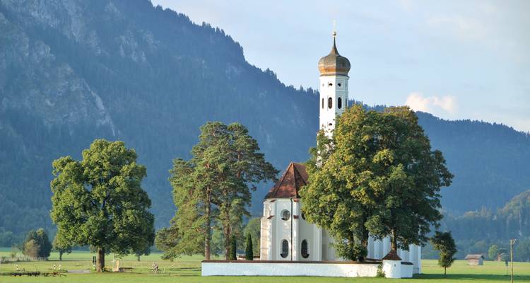 Eine malerische Kirche vor einer bergigen Kulisse.