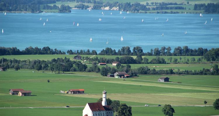 Eine Landschaft mit Feldern und einem See mit Bergen in der Ferne.