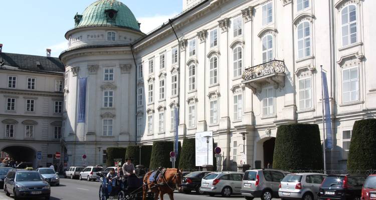 Un grand bâtiment historique avec une calèche devant.
