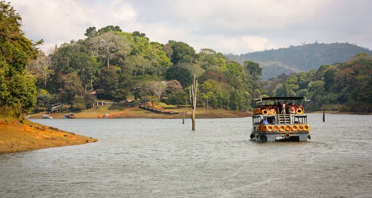 Touristenboot in einem ruhigen Fluss mit üppiger Kulisse