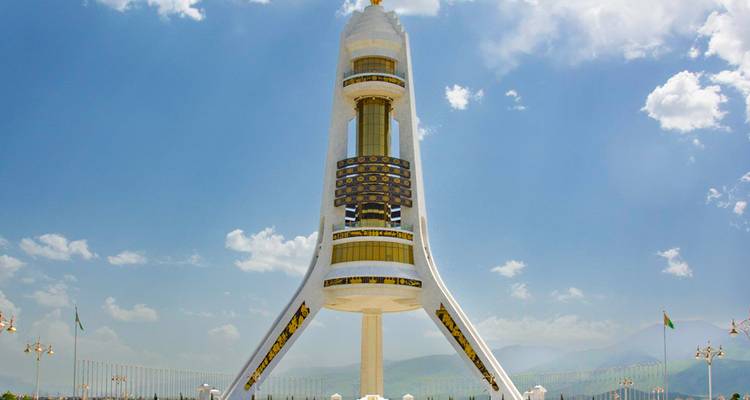 Une tour futuriste avec des sculptures en relief sur un fond montagneux.