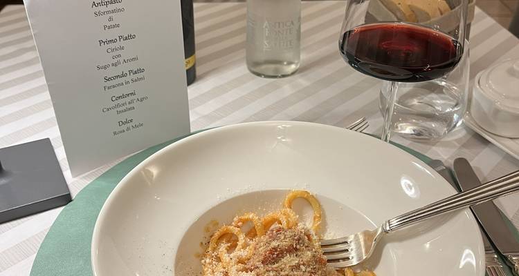 Plato de pasta con una copa de vino tinto en una mesa de comedor.