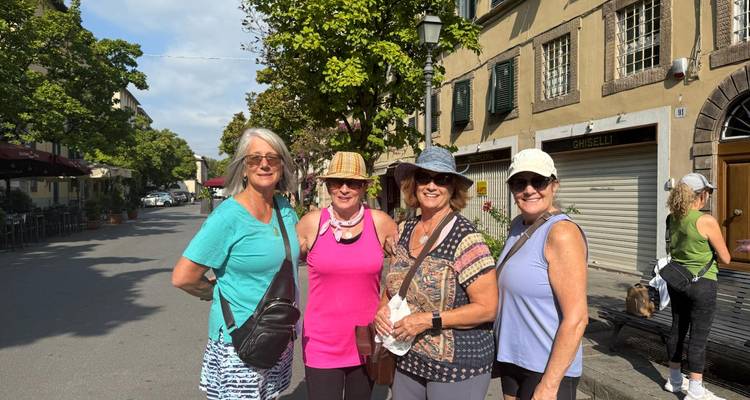 Grupo de mujeres posando en una calle con tiendas cerradas.