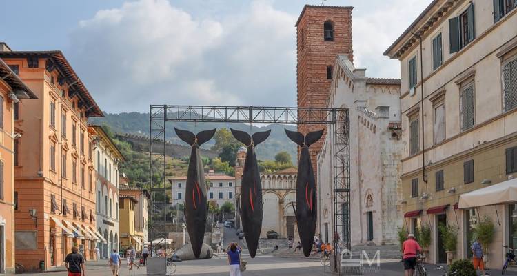 Escena callejera con escultura de arte moderno y edificios históricos.