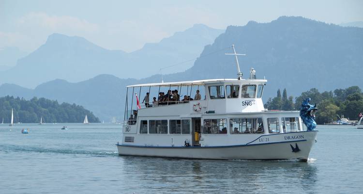 Un ferry sur un lac avec des montagnes en arrière-plan.