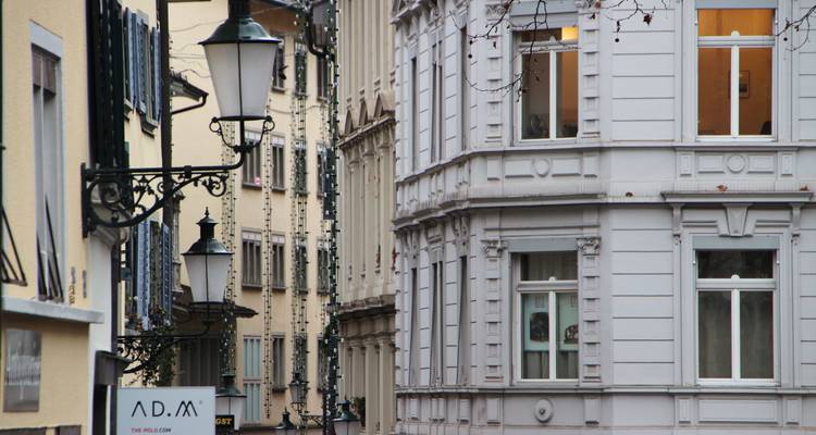 Une rue étroite avec de hauts bâtiments et des lampes décoratives.