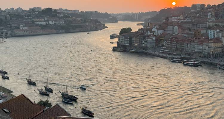 Vista del atardecer sobre un río con edificios de la ciudad.