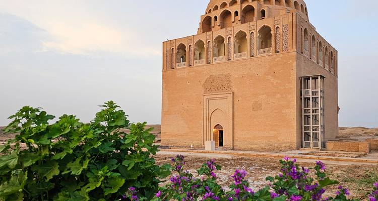 Un bâtiment historique carré avec des motifs de fenêtres complexes, entouré de verdure.