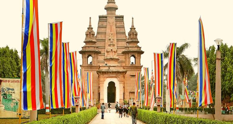 Eingang eines farbenfrohen Tempelkomplexes mit Fahnen und Touristen.