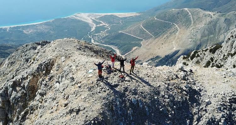 Grupo de personas en la cima de la montaña con vista al océano