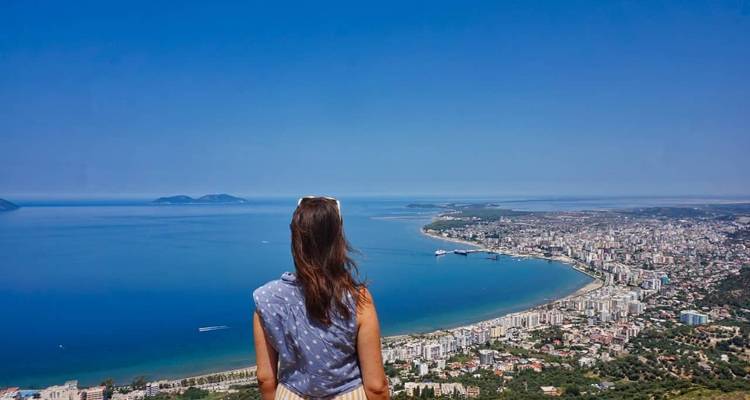 Mujer contemplando una ciudad costera y vista al océano