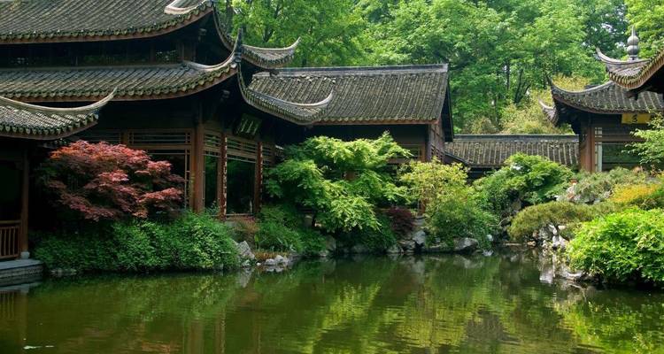 Traditioneel Chinees paviljoen bij een serene vijver, omringd door weelderig groen.