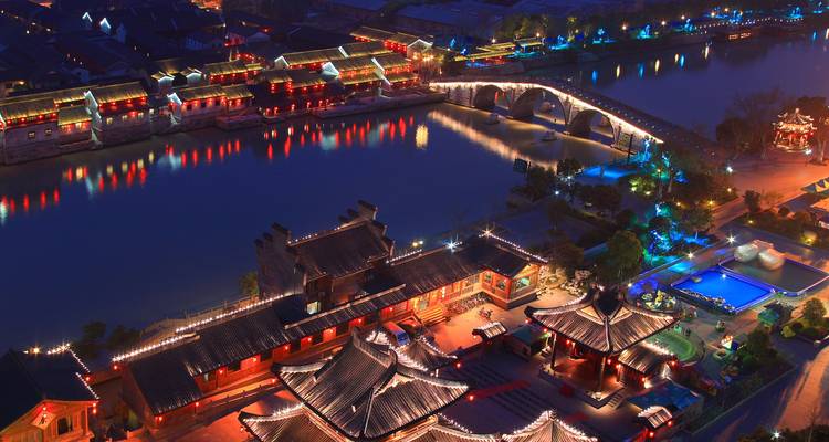 Nachtbeeld van een helder verlichte traditionele Chinese stad langs de rivier.