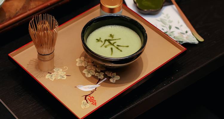 Gros plan d'un bol à thé avec des accessoires pour la préparation du thé sur un plateau décoré.