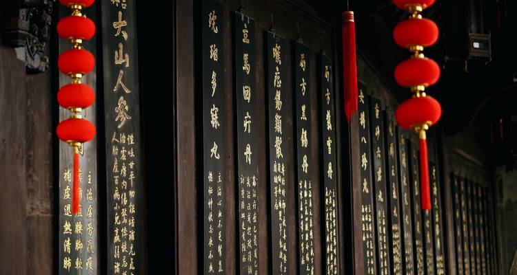 Rangée de panneaux noirs avec de la calligraphie chinoise dorée et des lanternes rouges.