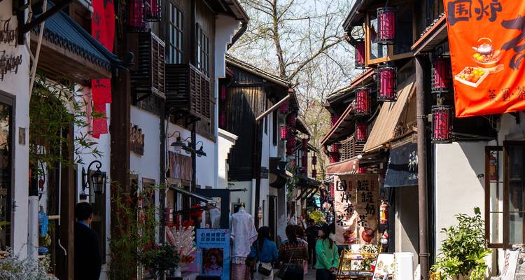 Rue animée dans une ville chinoise traditionnelle avec des lanternes rouges et des enseignes.