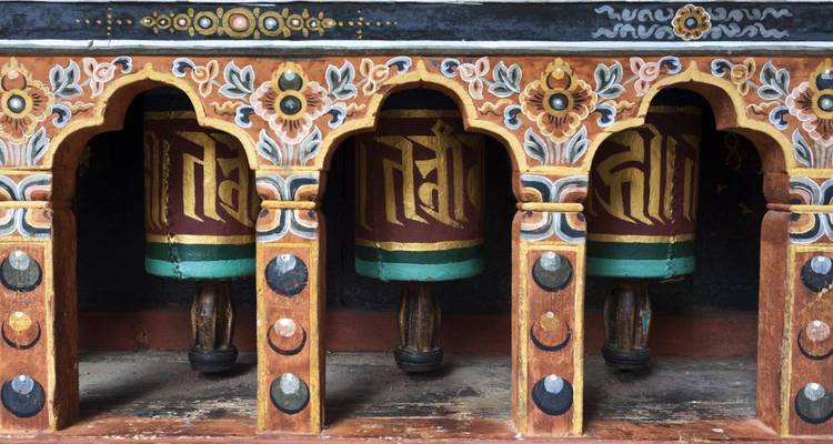 Moulins à prières colorés dans un cadre en bois sculpté de manière complexe.