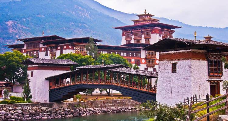 Dzong de Punakha avec un pont en bois au-dessus d'une rivière.