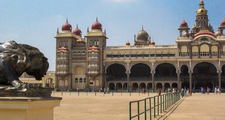 Mysore Palace met toeristen die rondlopen, grote boog zichtbaar op de voorgrond.