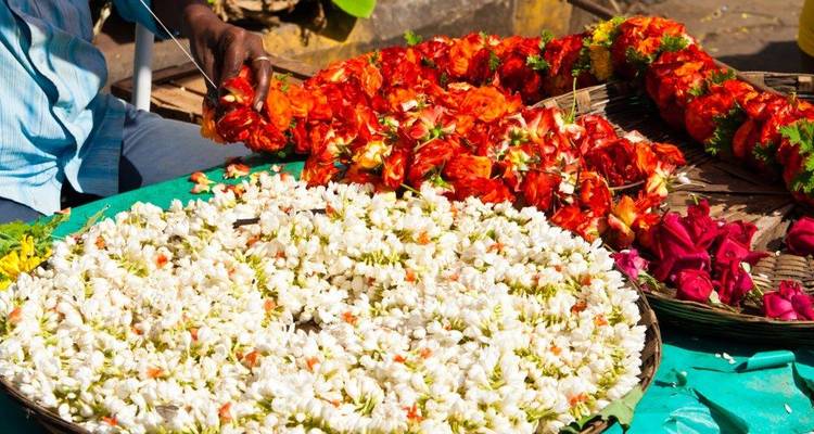 Bloemenstalletje met kleurrijke bloemen en koper die kransen uitzoekt.