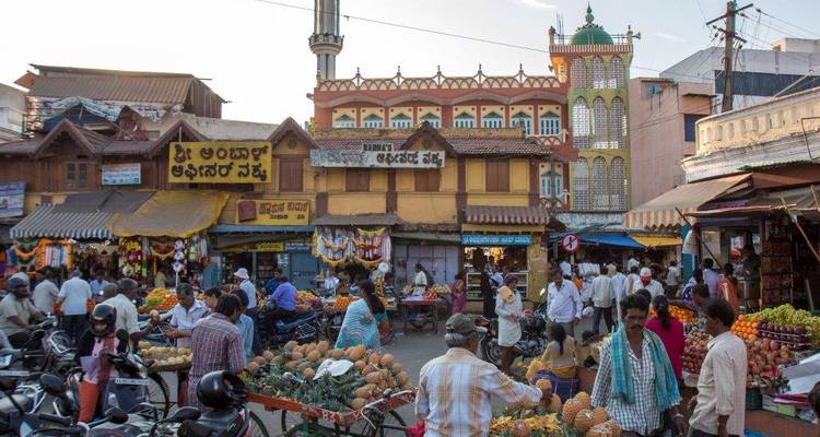 Drukke straatmarkt met mensen, winkels en kleurrijke uitstallingen.