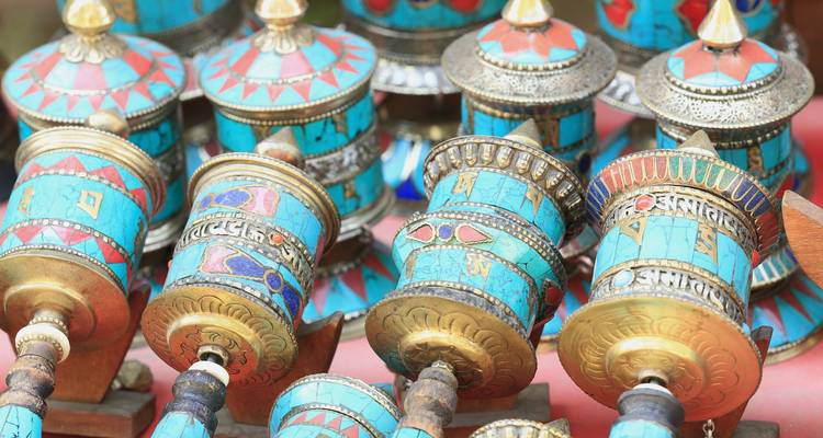 Ruedas de oración artesanales con diseños intrincados, exhibidas en un mercado.