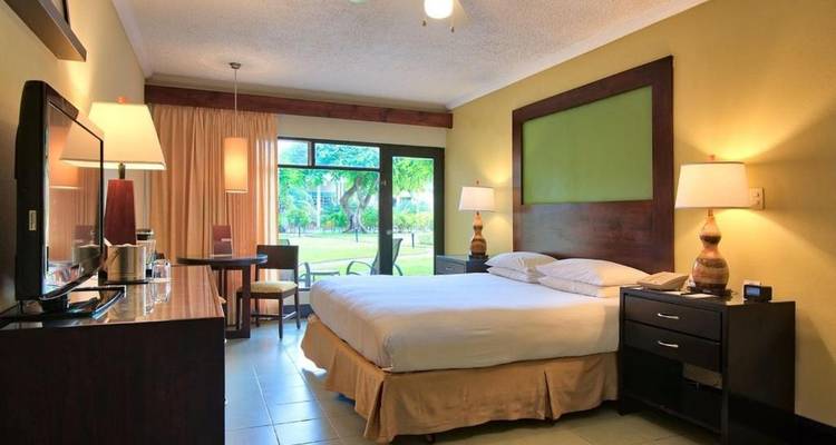 Hotelzimmer mit großem Bett und Fensterblick auf einen Garten