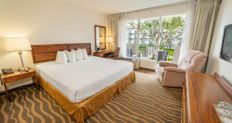 Helles Hotelzimmer mit einem großen Bett und Balkonblick nach draußen