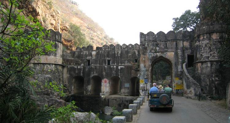 Des gens en safari en jeep près d'un fort de pierre ancien.