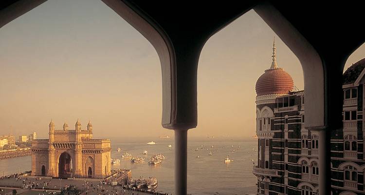 Une vue depuis une fenêtre montrant la Porte de l'Inde et un hôtel historique.
