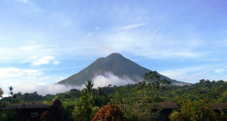 Vue d'un grand volcan avec des nuages et de la verdure.