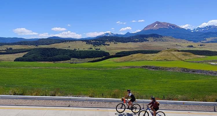 Cyclistes roulant à travers un vaste paysage avec des montagnes en arrière-plan.