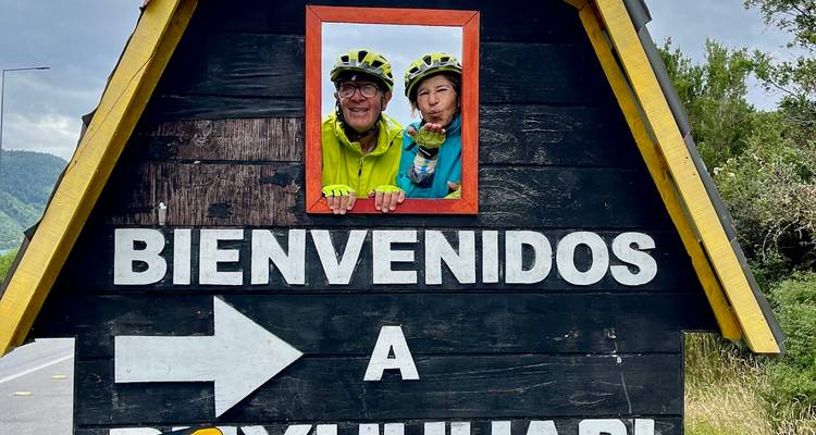 Deux personnes qui posent devant un panneau de bienvenue au bord de la route.