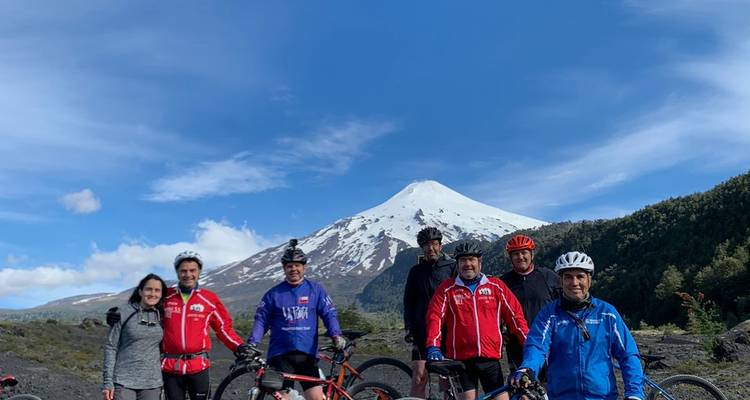 Groupe de cyclistes avec un volcan enneigé en arrière-plan.